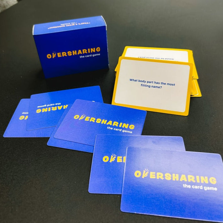 Oversharing card game components including cards and a blue box on a black surface